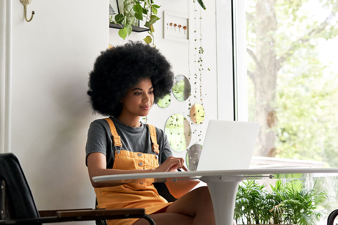 A girl working on a computer by the window