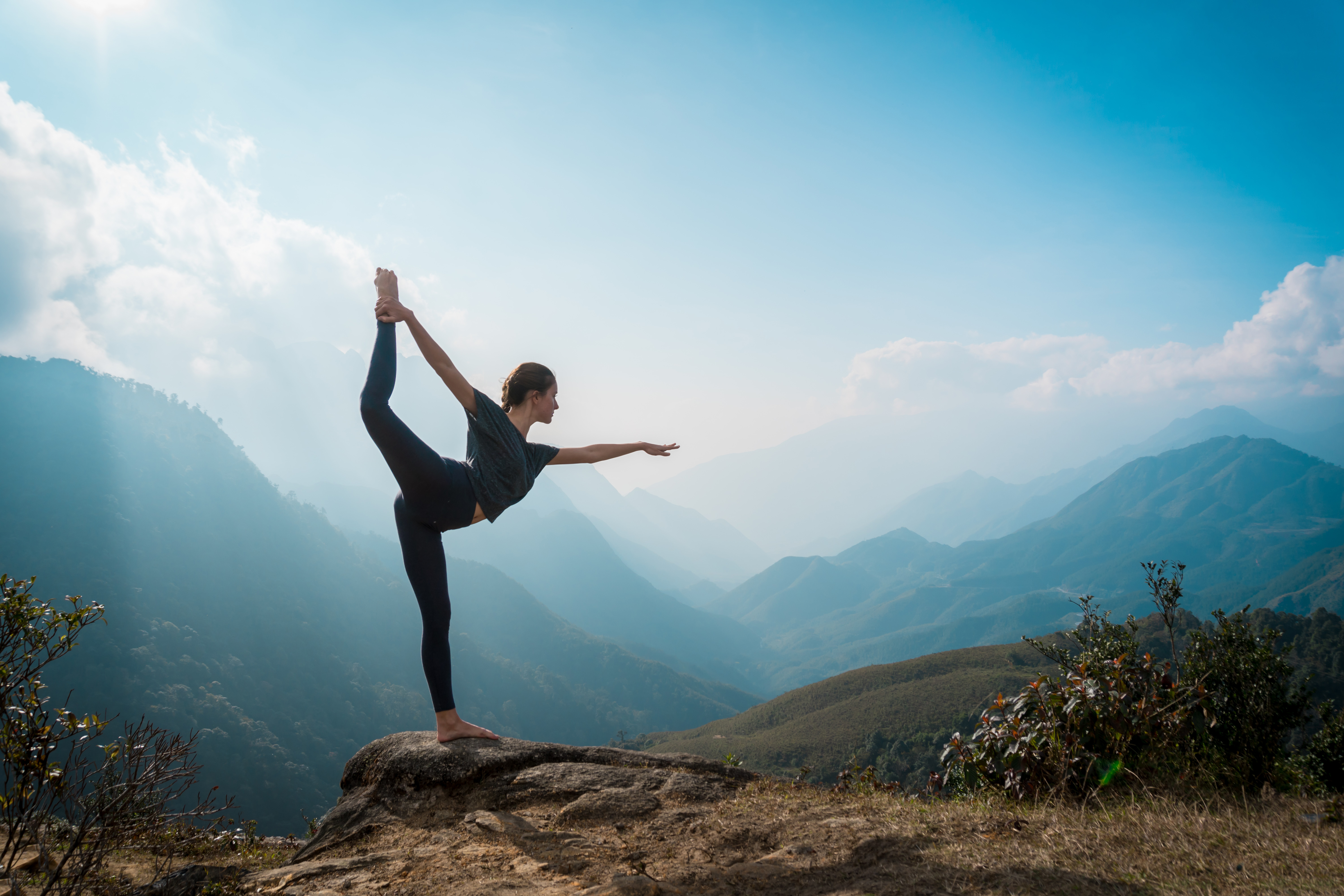 a young woman stretching her body on a mountaintop